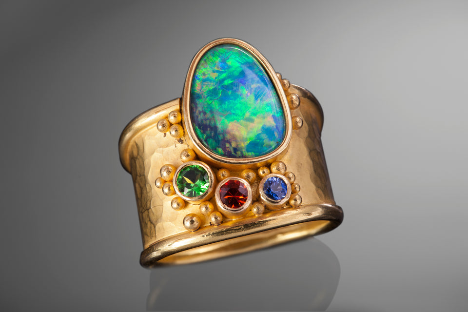 unique and custom ring made with a fiery opal and sapphires. This is an ancient inspired design and made with 14K yellow gold.