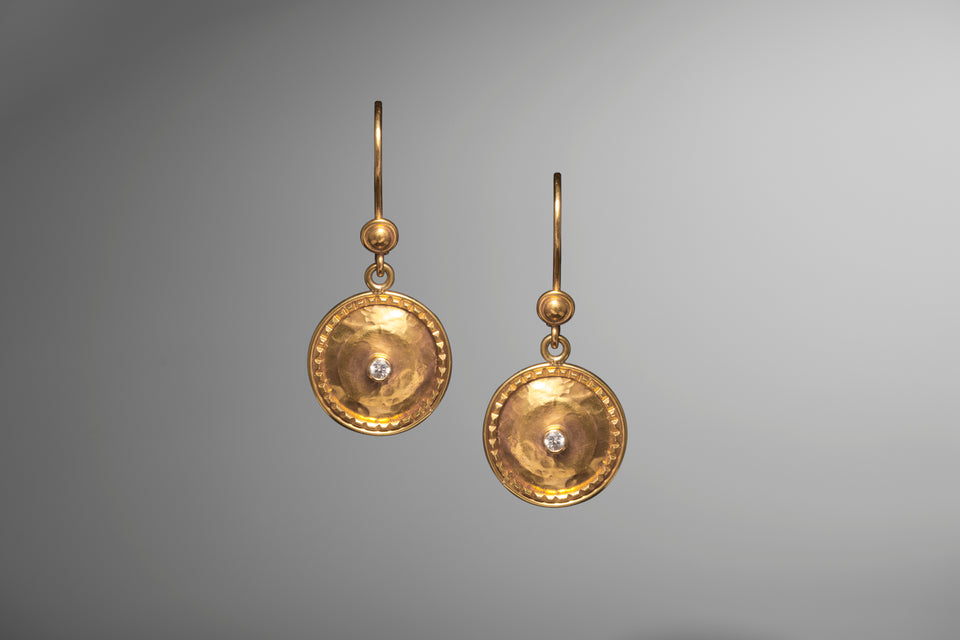 Short hanging earrings made with 18K yellow gold and two accent diamonds centrally located in this round earring disks. 
